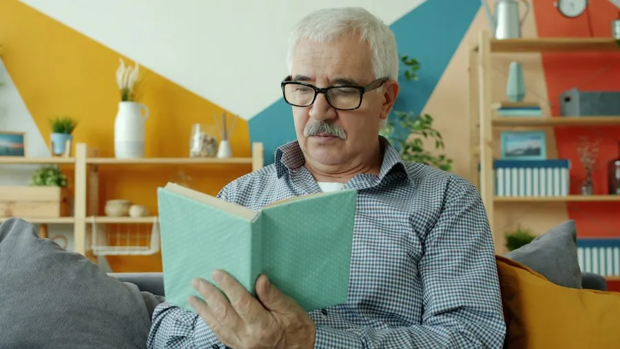 Hombre mayor con gafas leyendo un libro en su sala de estar